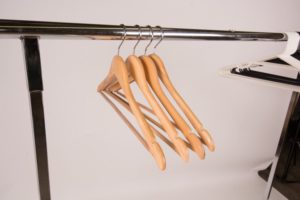 wooden hangers on a clothing rack