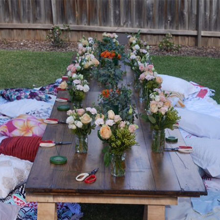 Boho picnic trestle table with flower bouquets in vases on hire