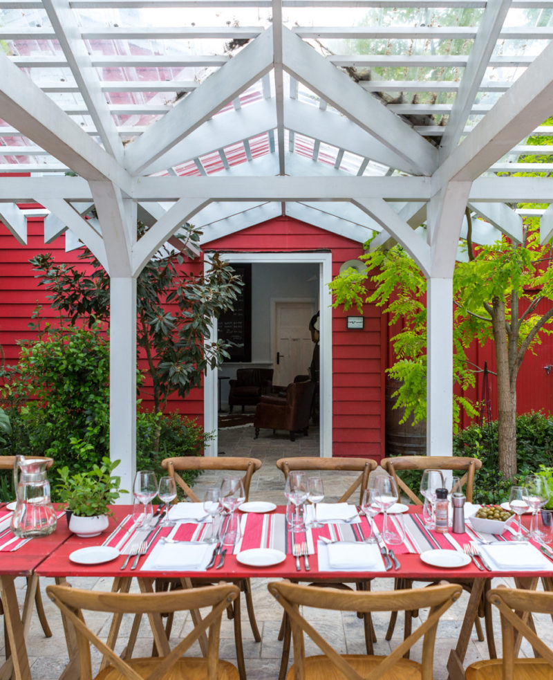 Red painted trestle tables in a line with wooden chairs on either side.