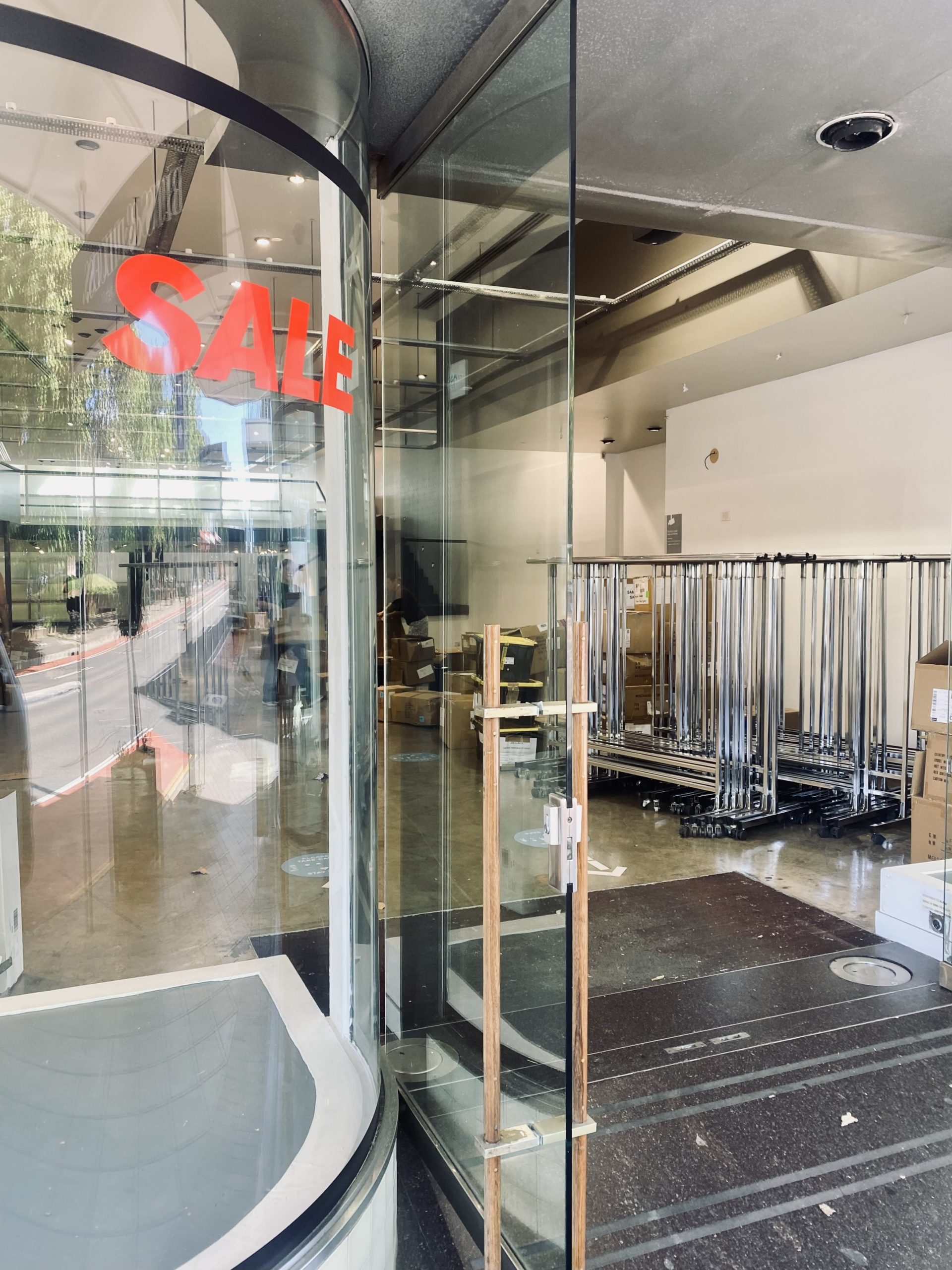 Looking into a pop up store with clothing racks in the background and a SALE sign on the glass window